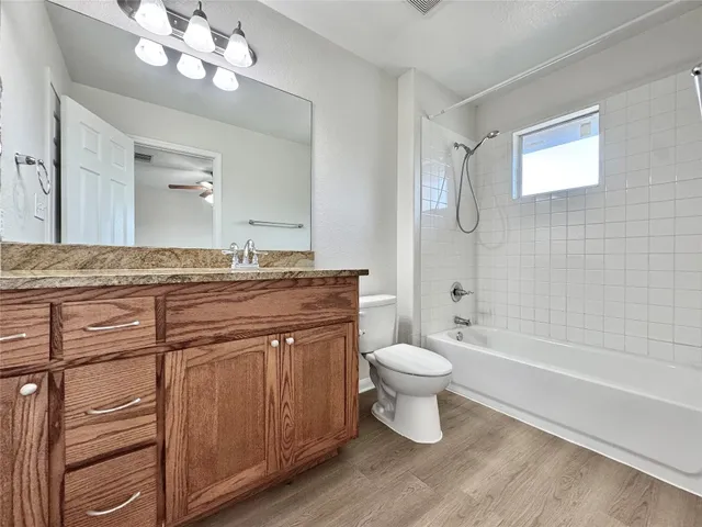 a bathroom with a granite countertop toilet a sink a mirror a bathtub and shower