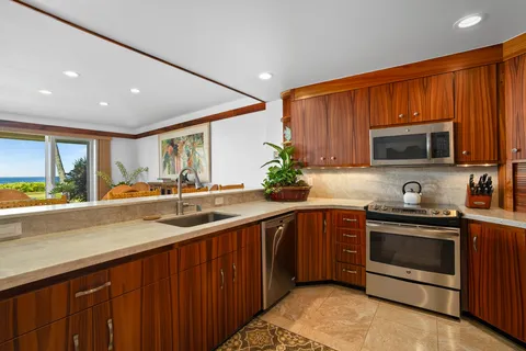 a kitchen with stainless steel appliances granite countertop wooden cabinets a stove a sink and a microwave