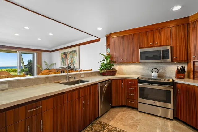 a kitchen with stainless steel appliances granite countertop wooden cabinets a stove a sink and a microwave
