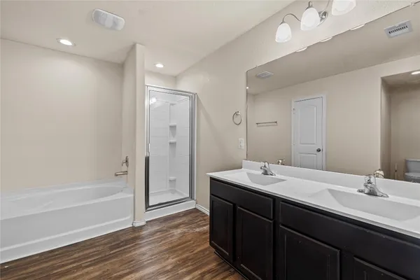 a bathroom with a tub sink double vanity and a mirror