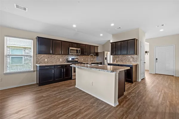 a large kitchen with a stove a sink dishwasher a microwave oven and a oven with wooden floor