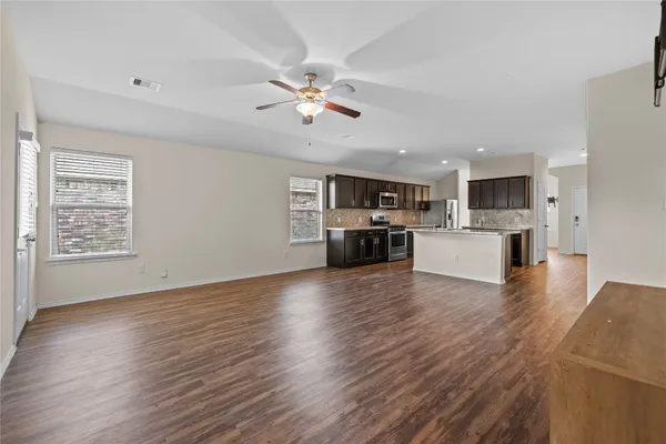 a view of kitchen with microwave a stove top oven and white cabinets with wooden floor