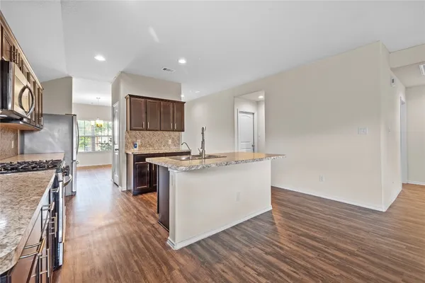 a kitchen with stainless steel appliances granite countertop a stove top oven a sink and a refrigerator