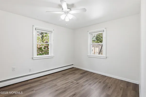 an empty room with wooden floor and a ceiling fan