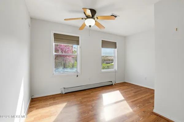 an empty room with wooden floor chandelier fan and windows
