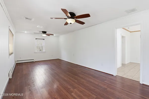 a view of empty room with wooden floor and ceiling fan