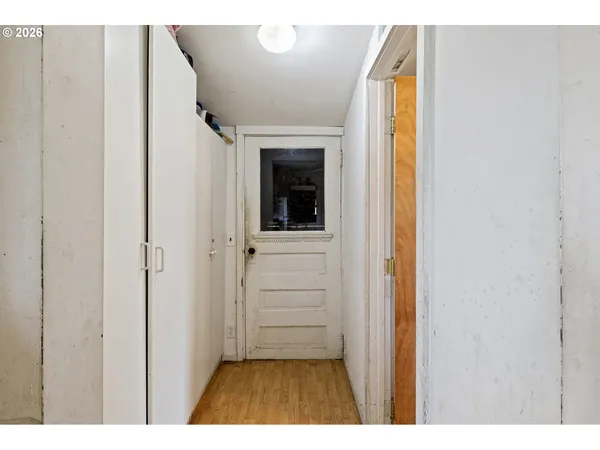 a view of a hallway with wooden floor and a bathroom
