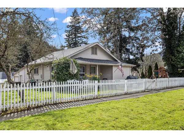 a front view of a house with a garden and trees