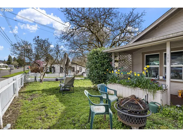a view of a backyard with table and chairs potted plants and a large tree