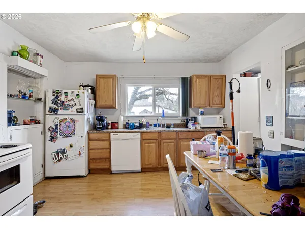 a kitchen with stainless steel appliances kitchen island granite countertop a refrigerator a sink dishwasher and white cabinets with wooden floor