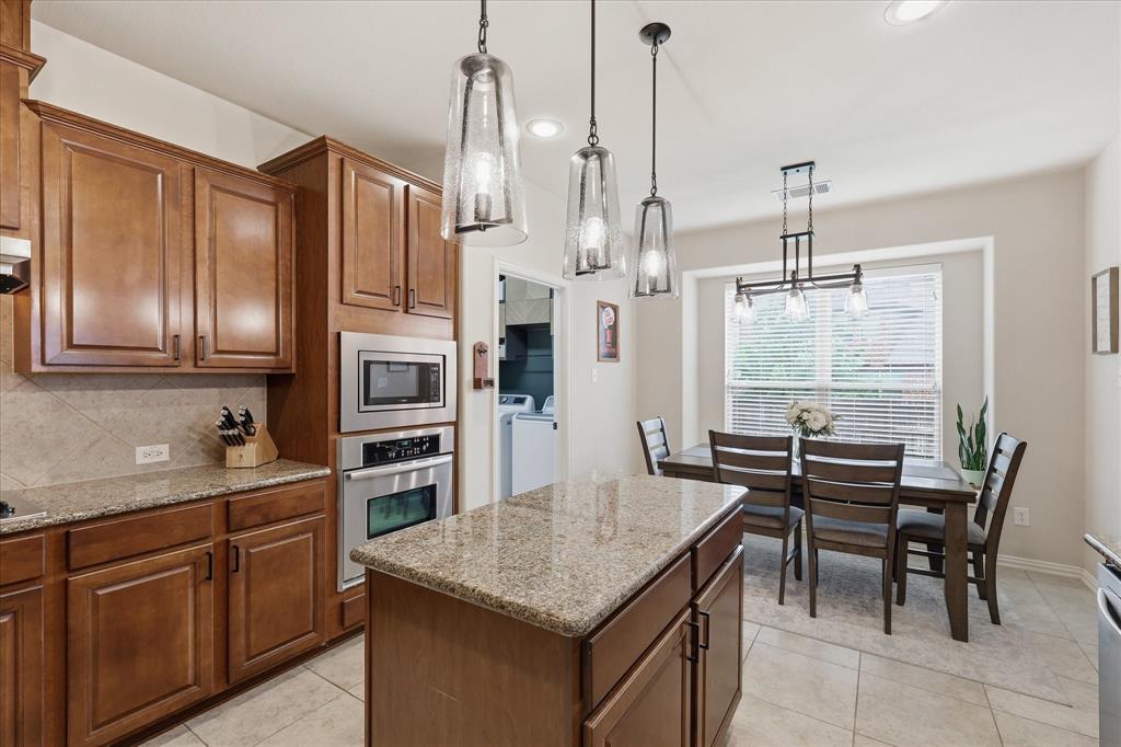 7105 Edwards Road Denton, TX 76208 - Photo 14 of 40 Open kitchen with updated light fixtures, granite countertops, island, and space for everyday dining.