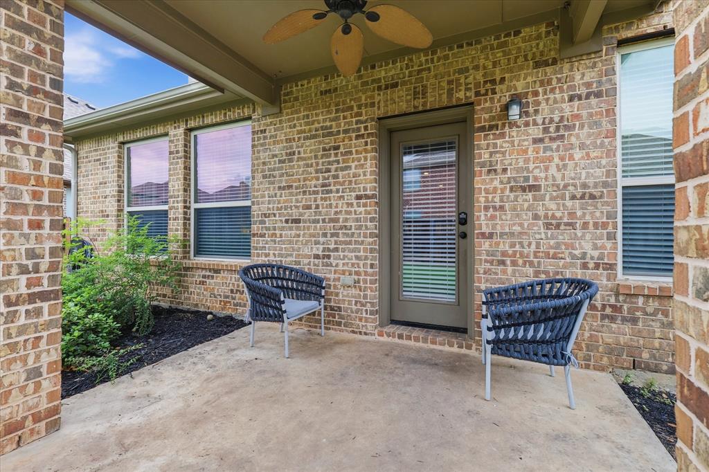 7105 Edwards Road Denton, TX 76208 - Photo 33 of 40 Covered backyard patio with ceiling fan and space for outdoor seating.