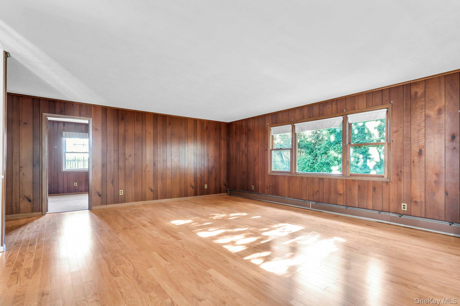 12 Violet Road Bayville, NY 11709 - Photo 16 of 42 Empty room featuring baseboard heating, light wood finished floors, and wood walls
