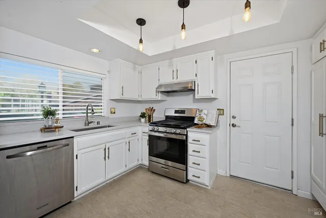 a kitchen with stainless steel appliances granite countertop a sink a stove and a refrigerator