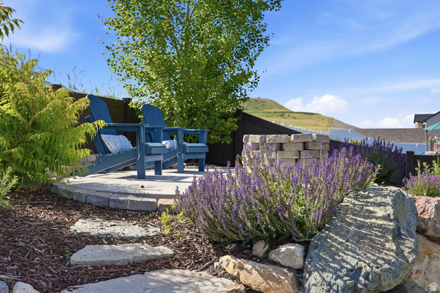 338 Windy Rdg Drive Smithfield, UT 84335 - Photo 57 of 63 Landscaped backyard area featuring a stone-paved patio, a built-in stone fire pit, and mature plantings