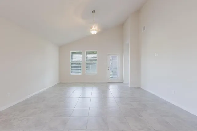an empty room with chandelier fan and windows