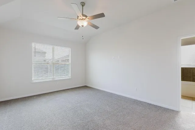 an empty room with a chandelier fan and windows