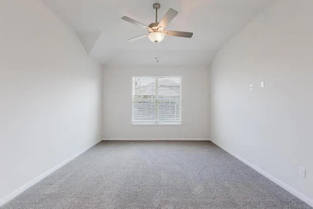 an empty room with a window and a ceiling fan