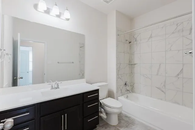 a bathroom with a bathtub shower sink vanity mirror and toilet