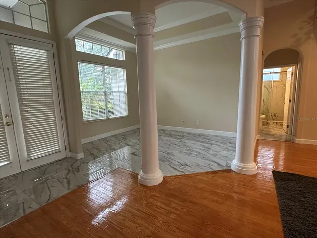 a view of empty room with wooden floor and fan