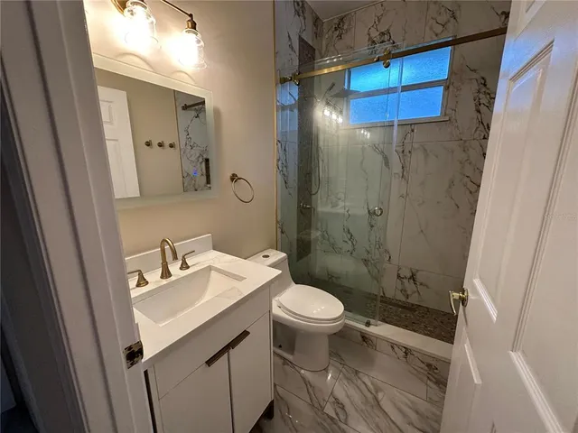 a bathroom with a sink toilet a mirror and shower