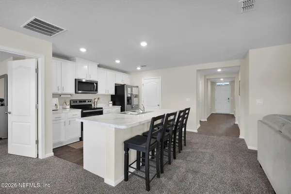 a view of kitchen with stainless steel appliances refrigerator stove microwave and dining table