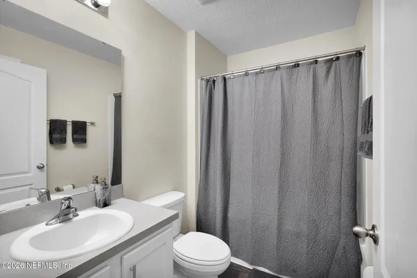 a bathroom with a sink a toilet a mirror and shower curtain