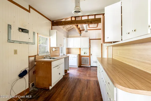 a kitchen with a sink appliances wooden floor and a large window