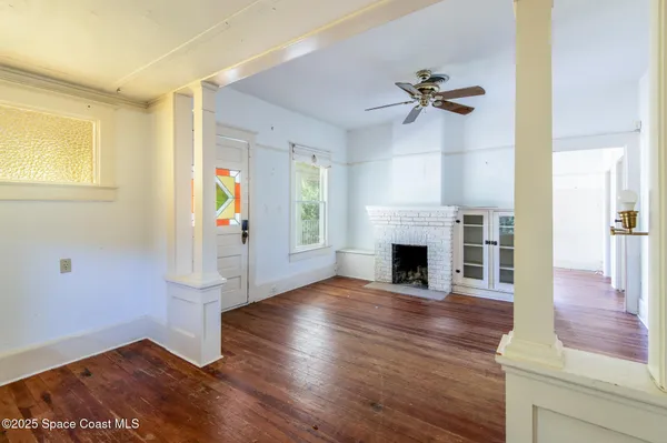 an empty room with wooden floor fireplace and windows