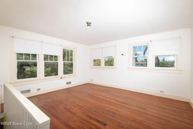 a view of an empty room with a window and wooden floor
