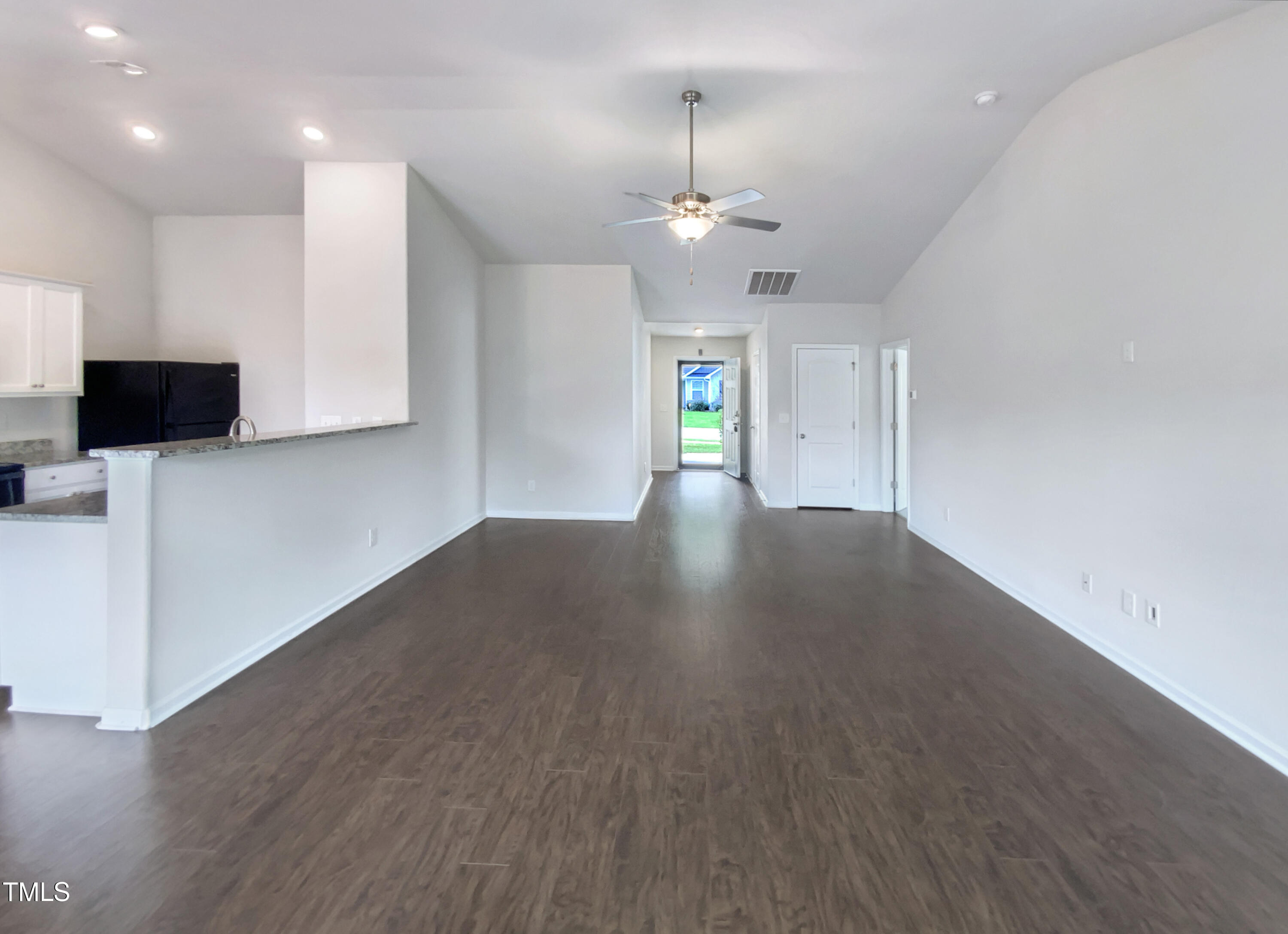 337 Rustling Way Zebulon, NC 27597 - Photo 10 of 19 a view of an empty room with wooden floor and a kitchen