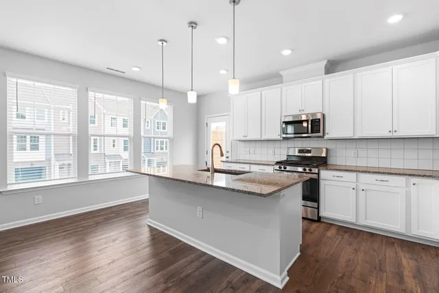 a kitchen with stainless steel appliances granite countertop a sink a stove and a wooden floors