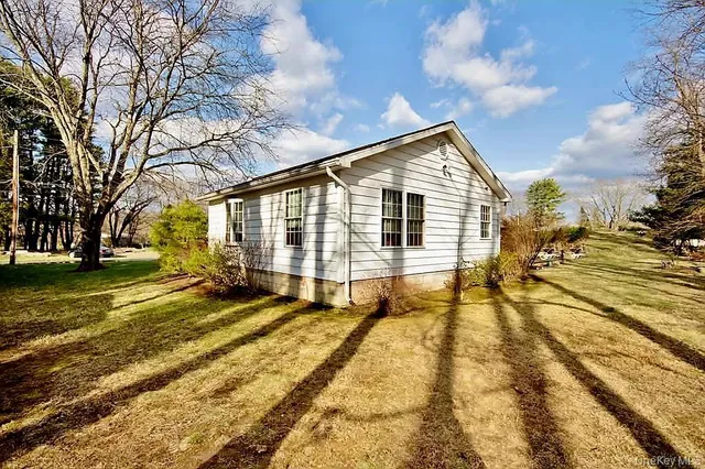 a view of a large white house with large trees and a yard