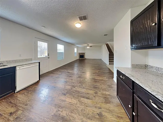 a view of a kitchen with kitchen island a sink wooden floor and a stove
