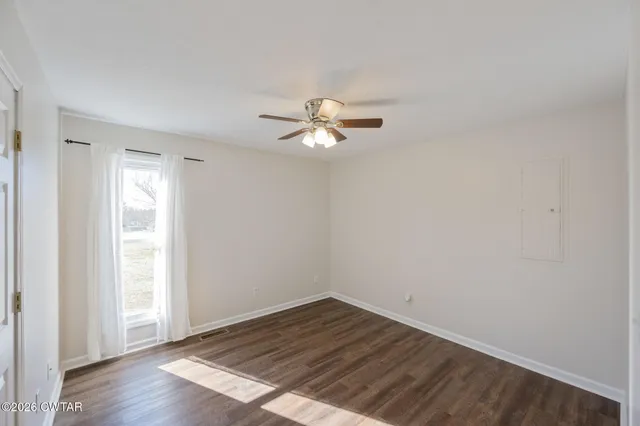 an empty room with wooden floor and ceiling fan