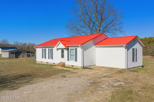 a view of a house with a yard and table and chairs under an umbrella