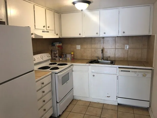 a kitchen with granite countertop white cabinets and white appliances