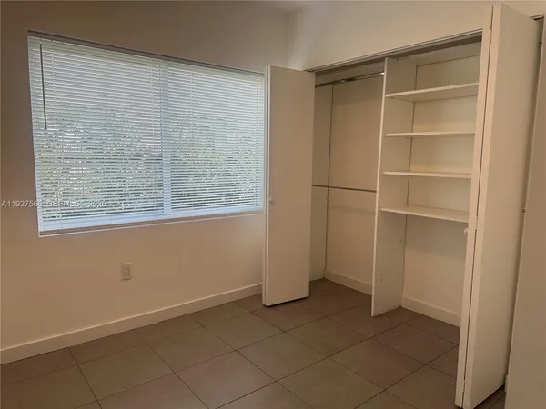 a view of an empty room with wooden floor and windows