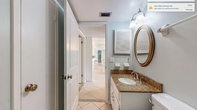 a bathroom with a granite countertop toilet a sink and a mirror