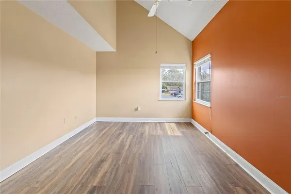 an empty room with wooden floor and windows