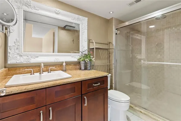 a bathroom with a sink vanity granite toilet and shower