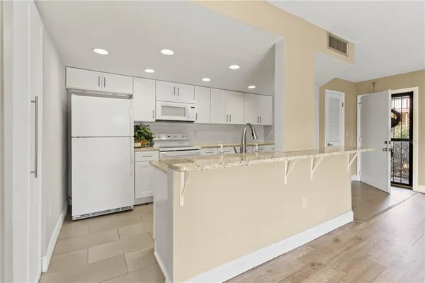 a view of kitchen with stainless steel appliances granite countertop cabinets and a refrigerator