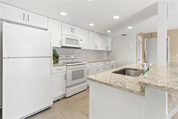 a kitchen with granite countertop white cabinets and white appliances