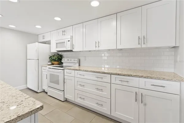 a kitchen with granite countertop white cabinets and white appliances