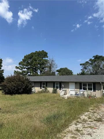 a front view of house with yard space and trees in the background