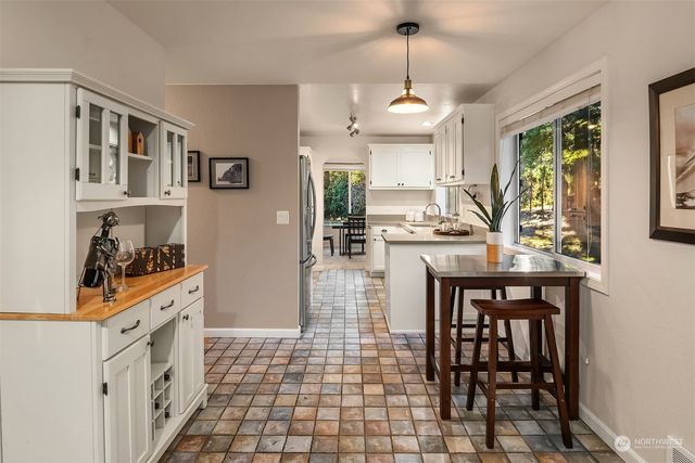 a kitchen with stainless steel appliances granite countertop a stove top oven a sink a dining table and chairs with wooden floor