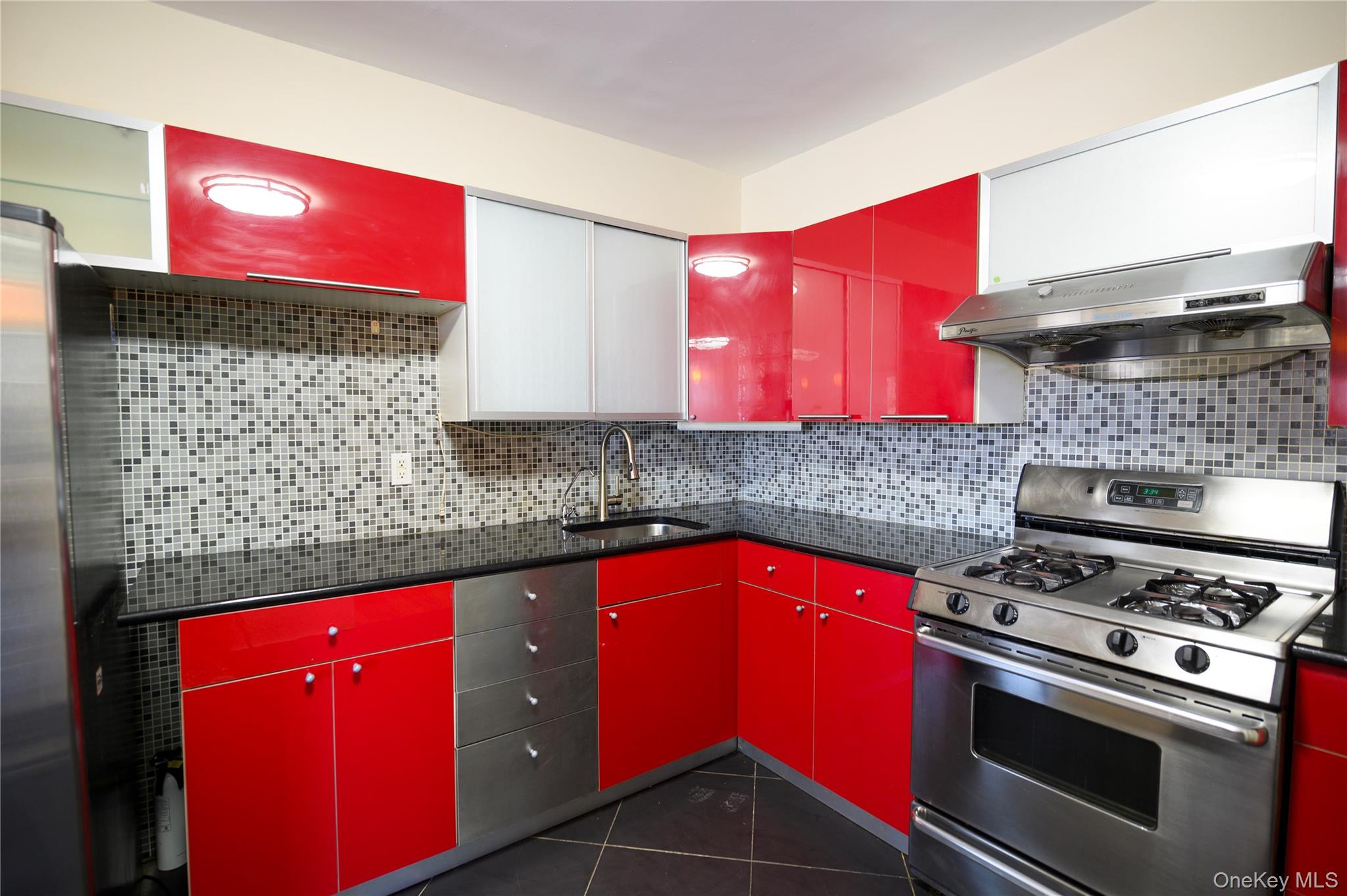 7124 164th Street, Unit 2 Queens, NY 11365 - Photo 13 of 22 a kitchen with stainless steel appliances a stove a sink cabinets and wooden floor