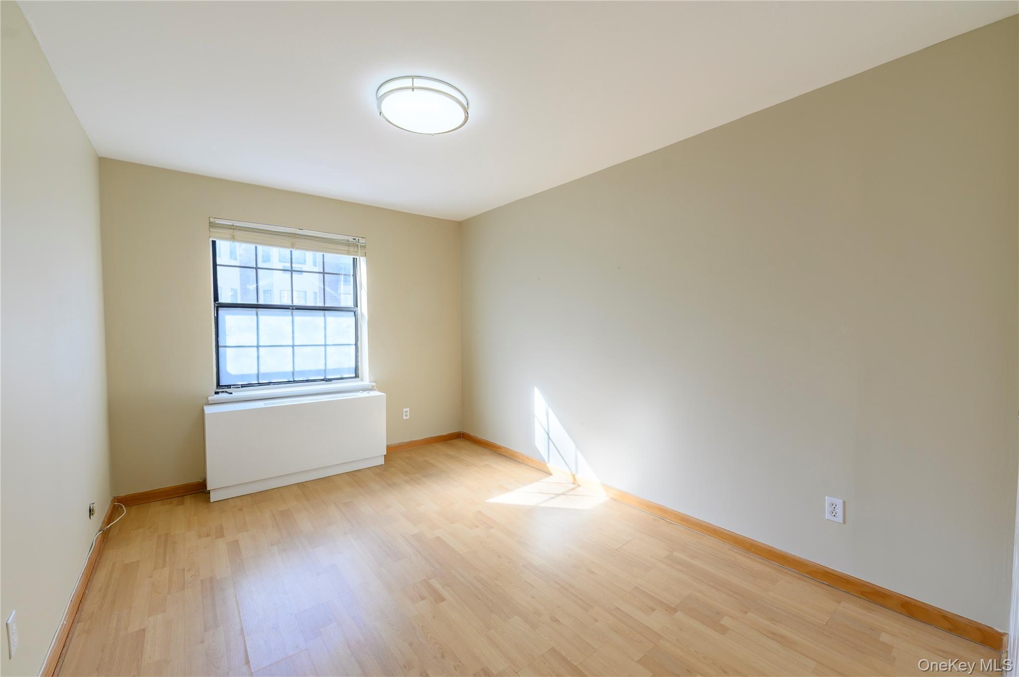 7124 164th Street, Unit 2 Queens, NY 11365 - Photo 16 of 22 an empty room with wooden floor and windows
