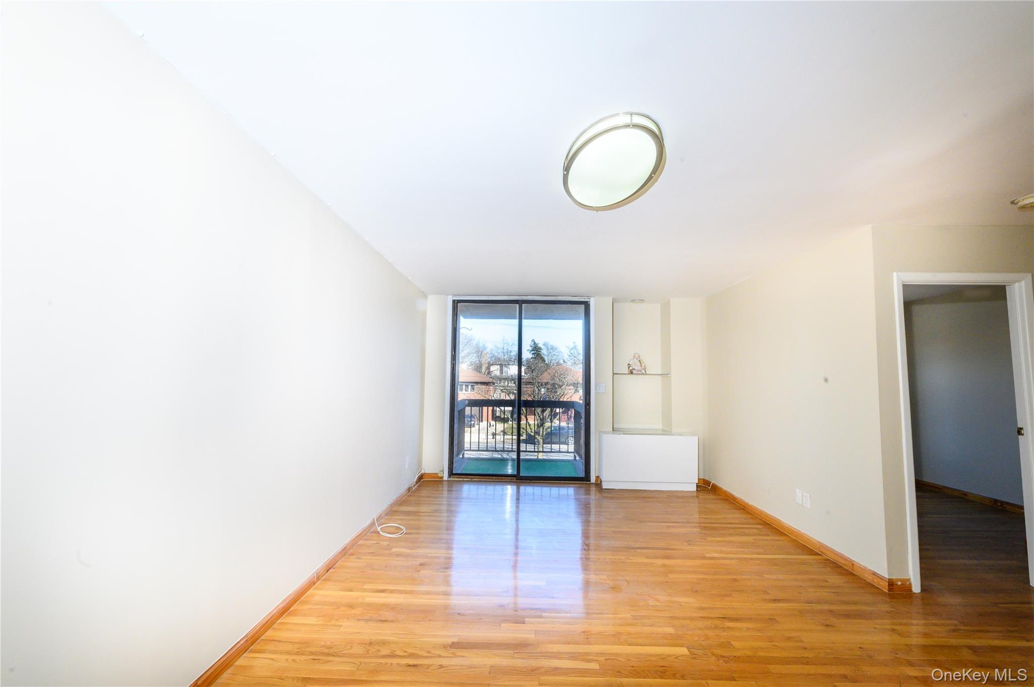 7124 164th Street, Unit 2 Queens, NY 11365 - Photo 3 of 22 a view of an empty room with window and wooden floor