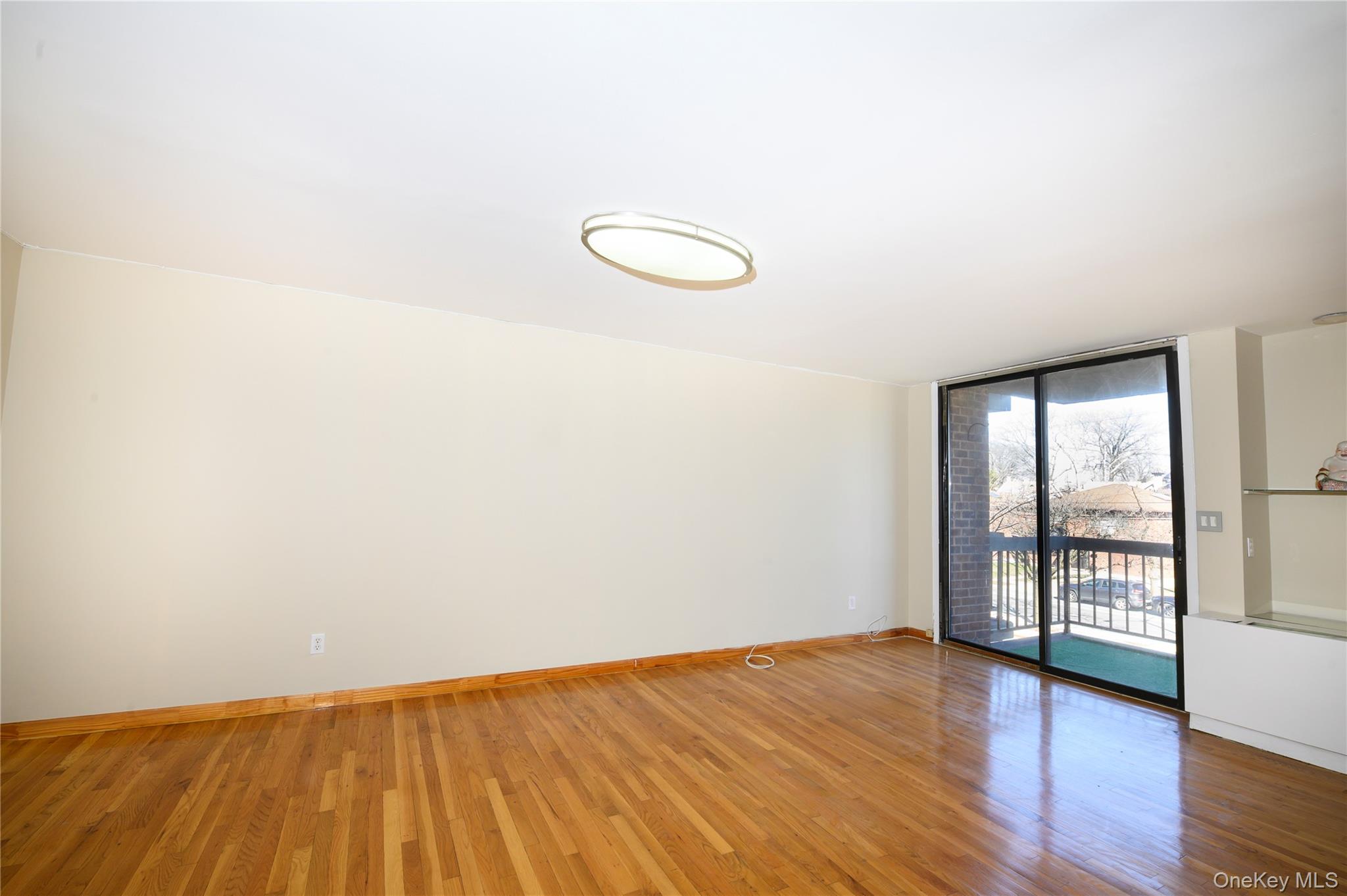 7124 164th Street, Unit 2 Queens, NY 11365 - Photo 6 of 22 an empty room with wooden floor and windows